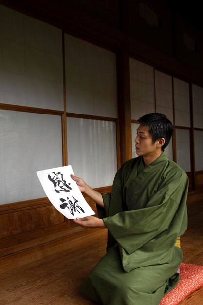 Homem segurando um papel com caligrafia japonesa