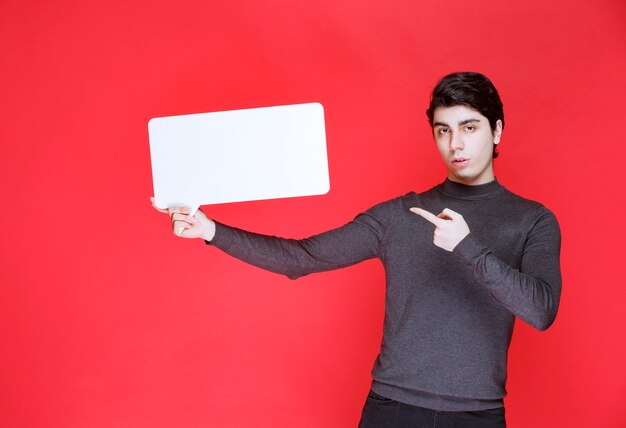 Homem segurando um quadro de ideias retangular e apontando para os participantes