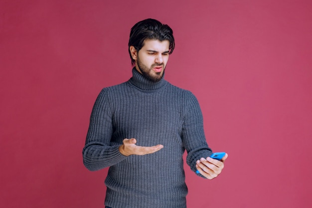 Homem segurando um smartphone e tentando entender suas funções.