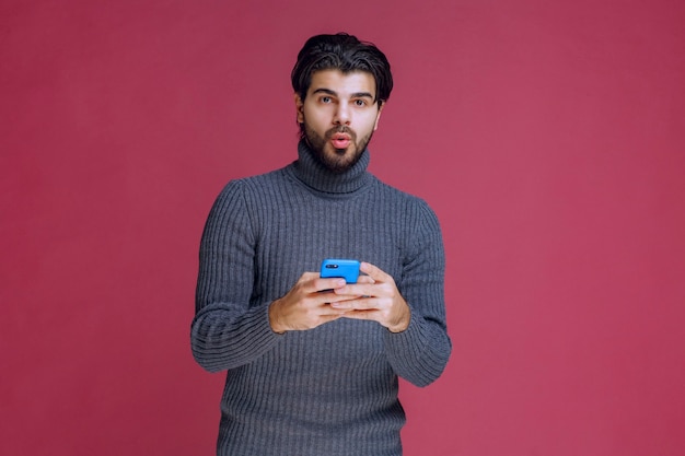 Homem segurando um smartphone, lendo mensagens ou mensagens de texto.