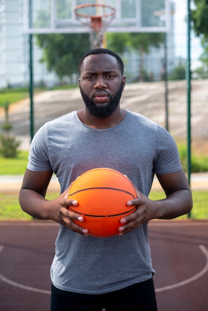 Foto grátis homem segurando uma bola na quadra de basquete plano médio