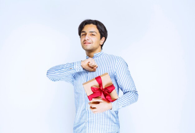 Homem segurando uma caixa de presente de papelão de fita vermelha e expressando sua gratidão. Foto de alta qualidade