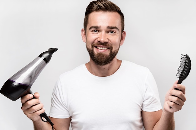 Foto grátis homem segurando uma escova e um secador de cabelo