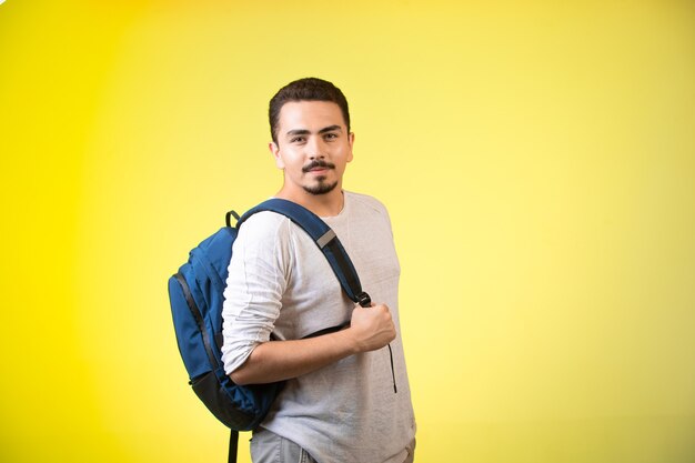 Homem segurando uma mochila azul e parece sedutor.