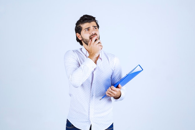 Homem segurando uma pasta azul e pensando