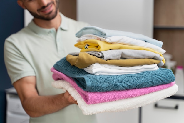 Foto grátis homem segurando uma pilha de roupas limpas