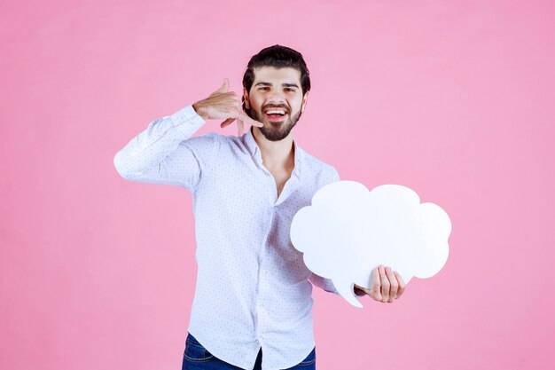 Homem segurando uma placa em forma de nuvem e pedindo uma ligação.