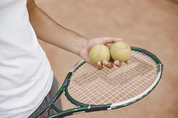 Homem segurando uma raquete e duas bolas de tênis