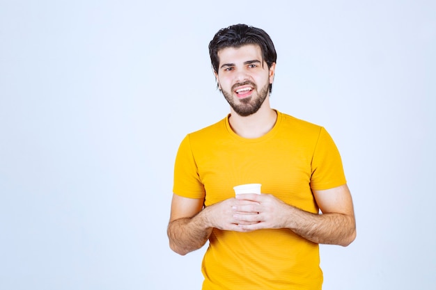 Homem segurando uma xícara de café descartável entre as mãos.