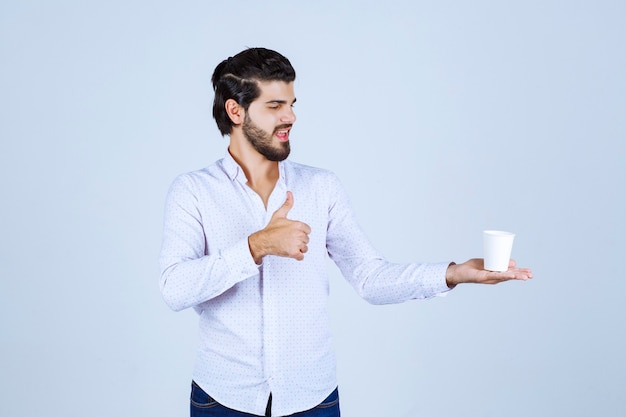 Homem segurando uma xícara de café e apreciando o sabor