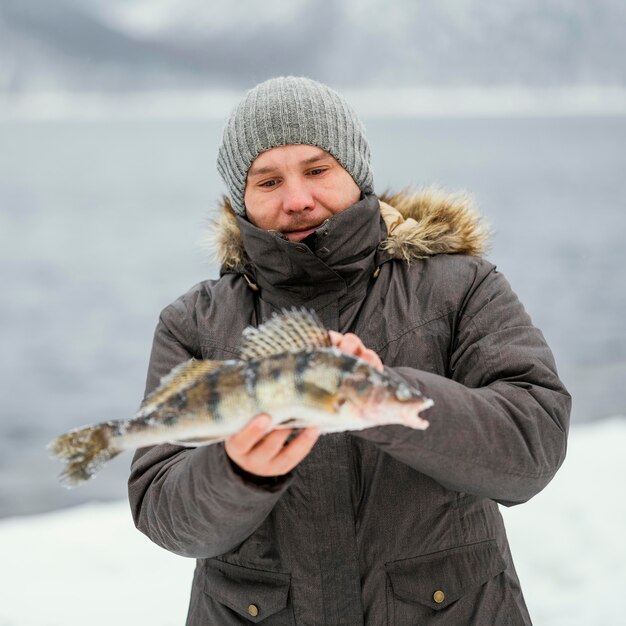 Homem segurando vitoriosamente um peixe que pegou