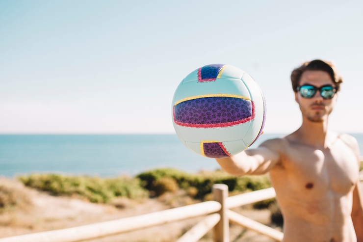 Foto grátis homem segurando voleibol na praia