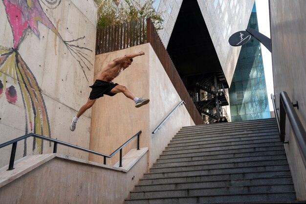 Homem sem camisa praticando parkour ao ar livre