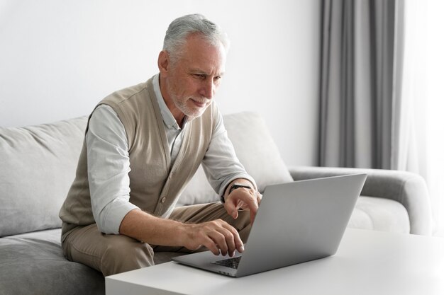 Homem sênior de tiro médio com laptop