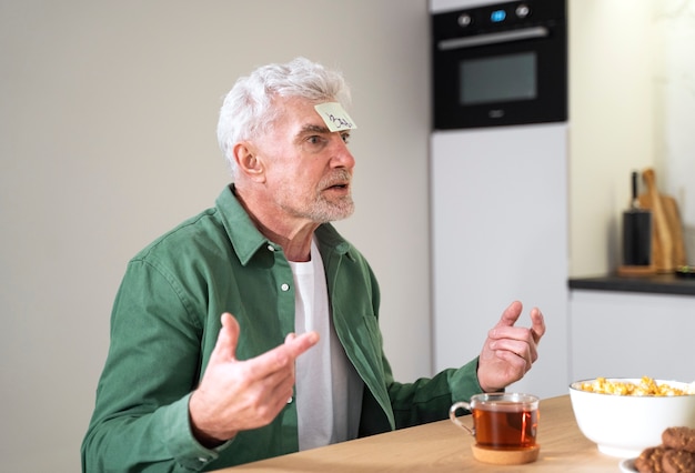 Homem sênior de tiro médio sentado à mesa