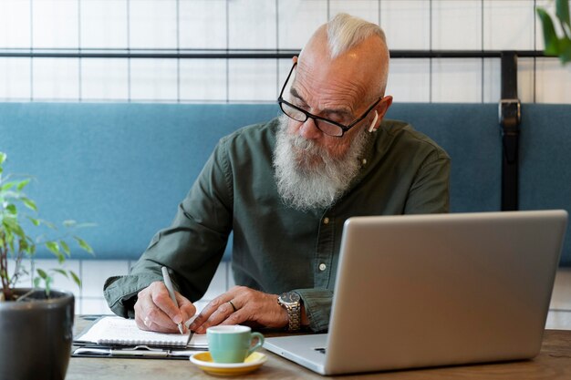 Homem sênior em tiro médio tomando notas