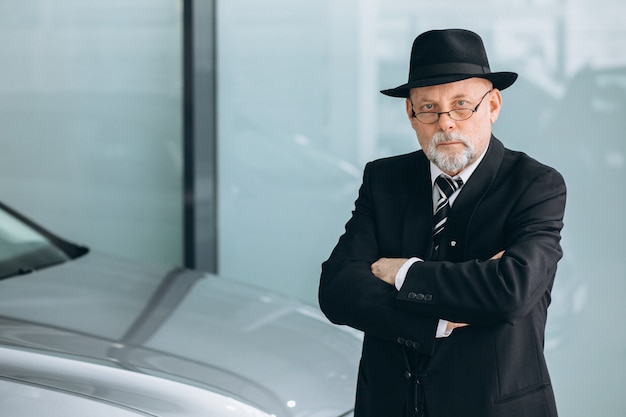 Foto grátis homem sênior em um showroom de carro, escolhendo um carro