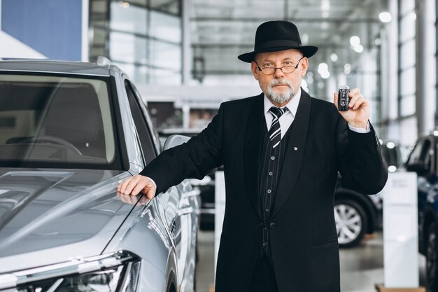 Homem sênior em um showroom de carro, escolhendo um carro