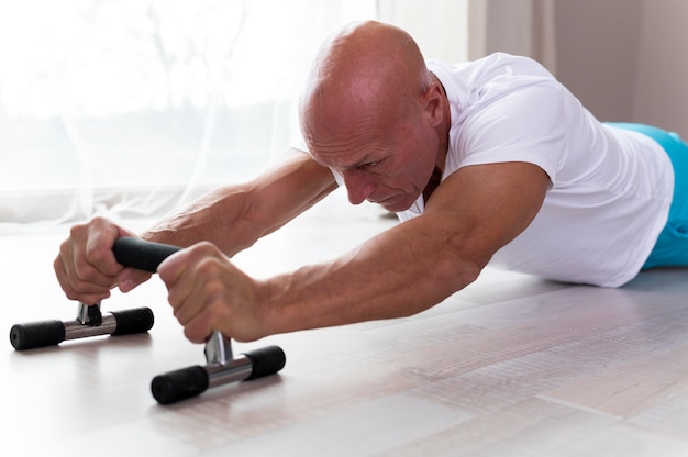 Foto grátis homem sênior fazendo exercícios dentro de casa