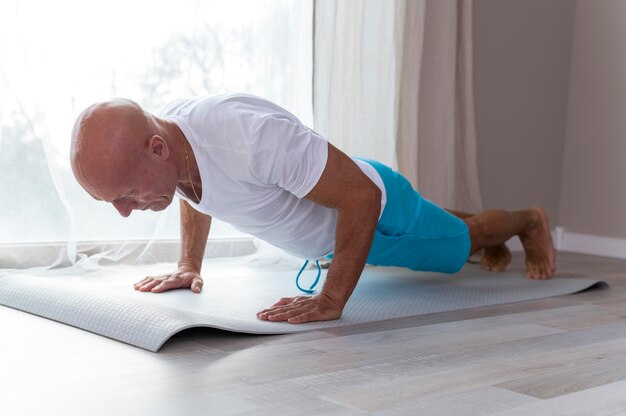 Foto grátis homem sênior fazendo exercícios esportivos ao lado da janela