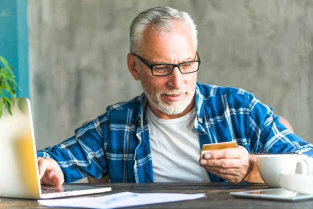 Homem sênior, leitura, crédito, cartão, número, enquanto, trabalhando, laptop