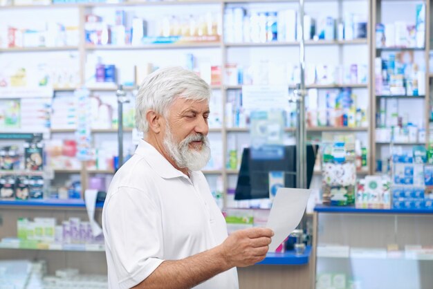 Homem sênior lendo prescrição em boticário