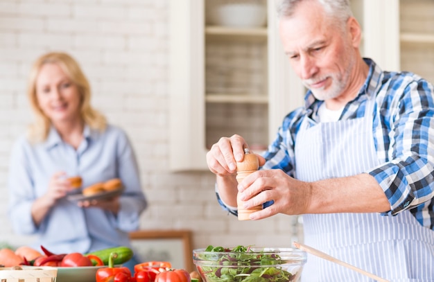 Foto grátis homem sênior, moer, pimenta, para, salada, e, dela, esposa, desfrutando, a, muffins, em, fundo, em, a, cozinha