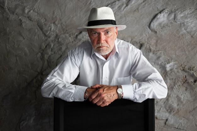 Homem sênior posando de camisa branca e chapéu