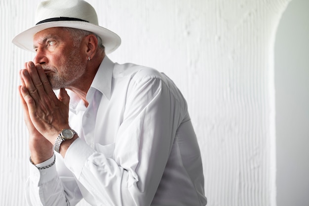 Foto grátis homem sênior posando de camisa branca e chapéu