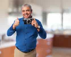 Foto grátis homem sênior que sorri com uma câmera velha da foto