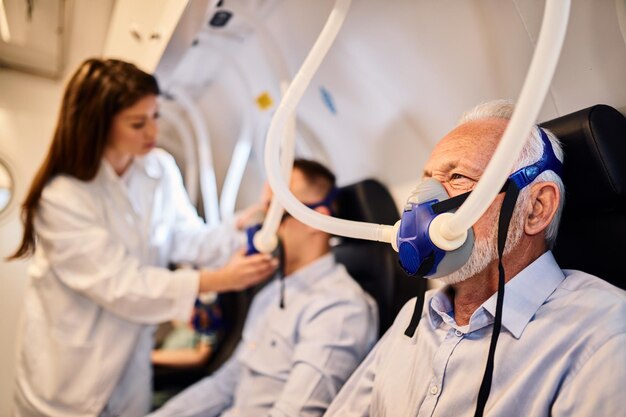 Homem sênior respirando através da máscara durante a oxigenoterapia na câmara hiperbárica