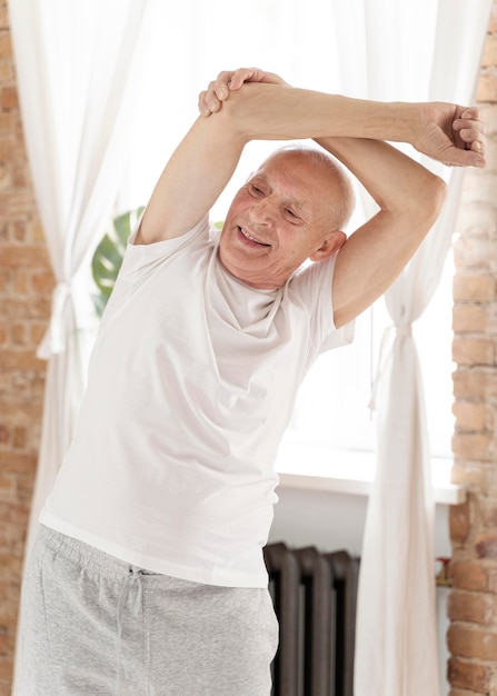 Foto grátis homem sênior sorridente de tiro médio alongando