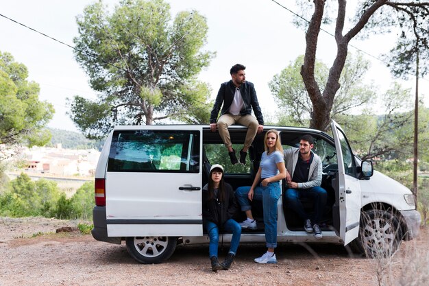 Homem sentado em cima do carro com os amigos