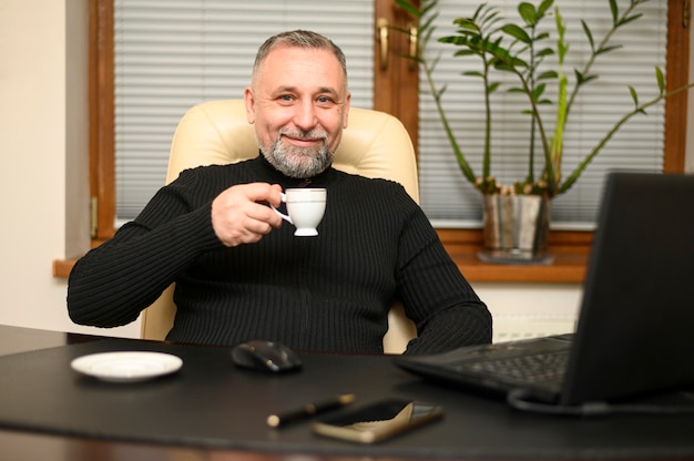 Homem sentado em sua mesa com uma xícara de café