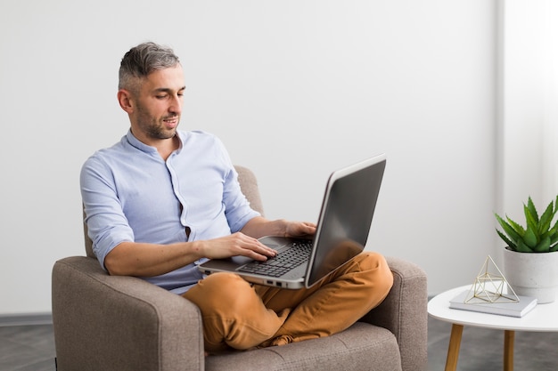 Homem sentado na cadeira e escrevendo no seu laptop