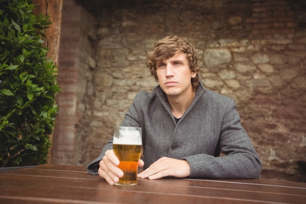 Homem sentado no bar com um copo de cerveja na mesa