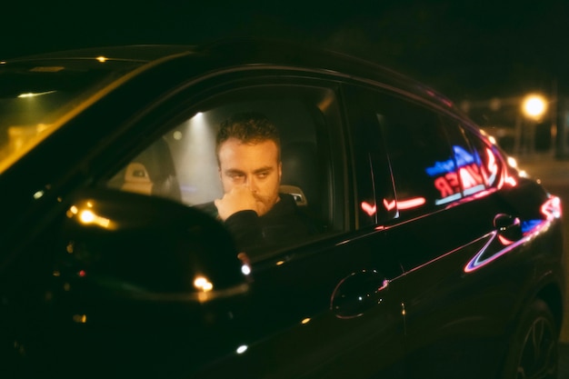 Homem sentado no carro a noite