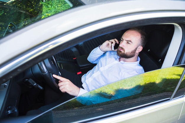 Foto grátis homem sentado no carro falando no smartphone