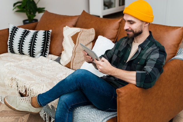 Homem sentado no sofá e olhando no tablet