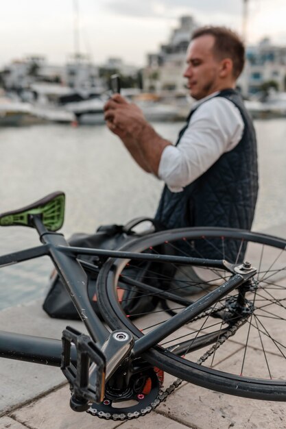 Homem sentado tirando uma foto ao lado de sua bicicleta