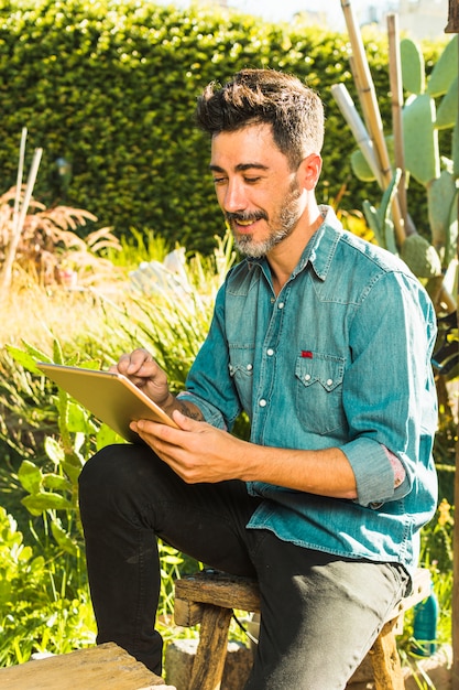 Homem, sentando, ao ar livre, parque, usando, tablete digital