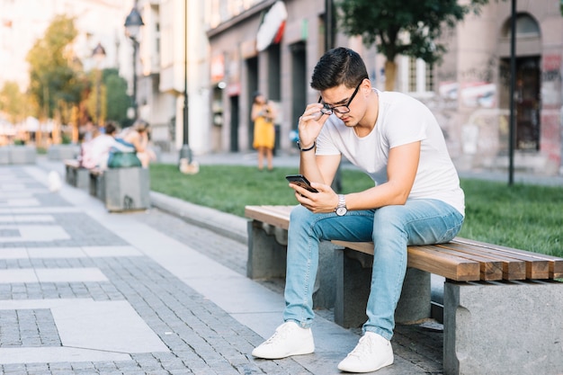 Homem, sentando, ligado, banco, usando, telefone móvel