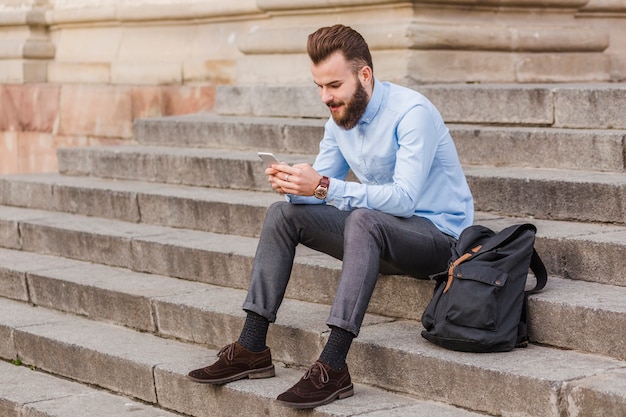 Homem, sentando, ligado, escadaria, usando, cellphone