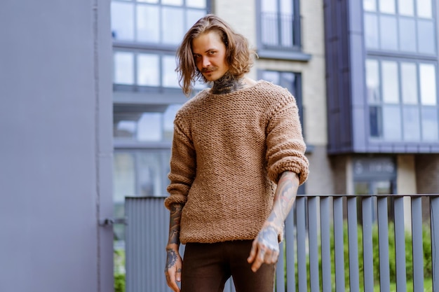 Foto grátis homem sexy tatuado bonito com cabelo comprido e bigode em uma camisola de malha. retrato fora de close-up.