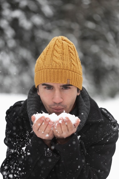 Homem soprando em uma pilha de neve