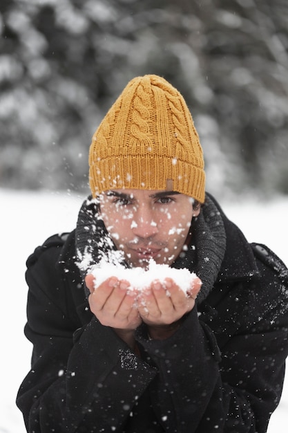 Homem soprando em uma pilha de vista frontal de neve