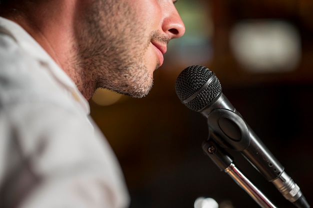 Homem sorridente cantando ao microfone em um bar desfocado