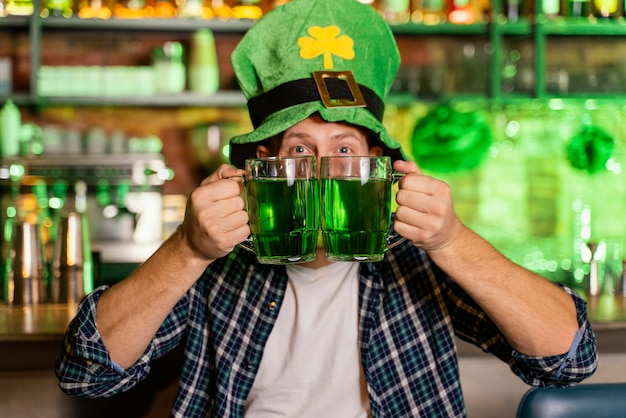 Homem sorridente celebrando st. dia de patrick no bar com cerveja