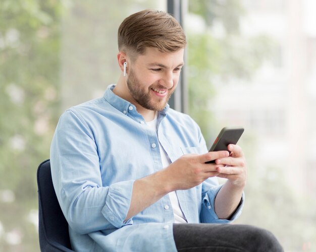 Homem sorridente com airpods usando o telefone