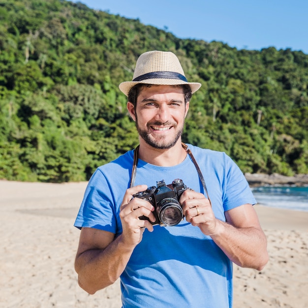 Foto grátis homem sorridente com câmera na praia